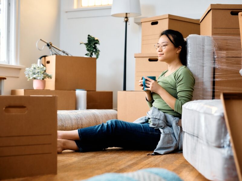 Young,Asian,Woman,Sitting,On,The,Floor,Among,Cardboard,Boxes